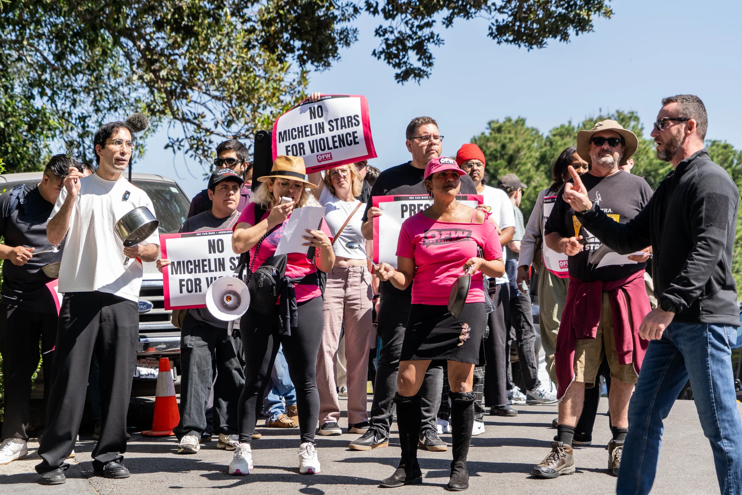 Members of One Fair Wage protest with signs stating "NO MICHELIN STARS FOR VIOLENCE".