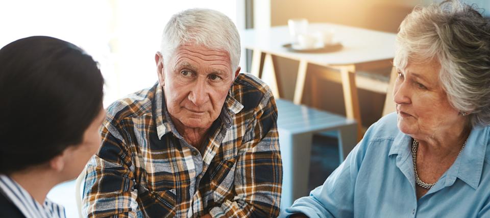 An older couple sit at a table chatting with a financial advisor.
