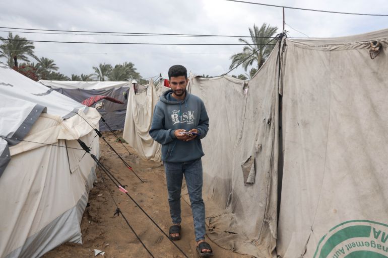 Abdel Karim Salman heads daily to the charging station to charge his phone and his wife’s phone, which they use as a source of light in their tent throughout the night [Abdelhakim Abu Riash/ Al Jazeera]