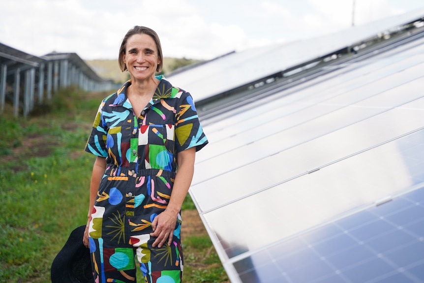 A woman smiling next to solar panels