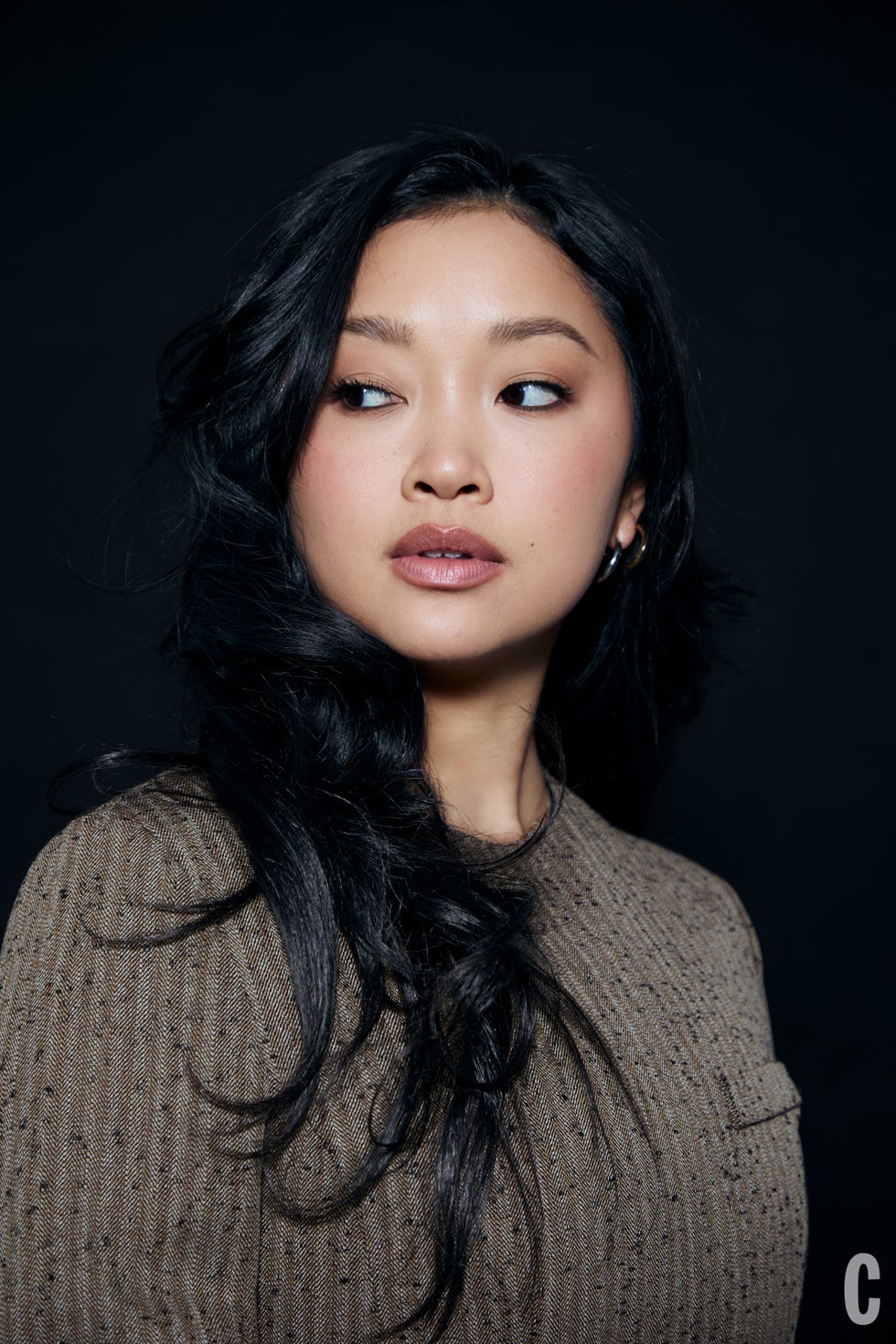 Portrait with obscured face, featuring long black hair and a textured brown sweater.