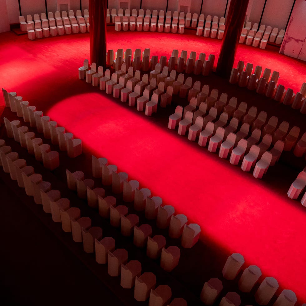 Arrangement of white chairs in a circular layout with a red carpet.