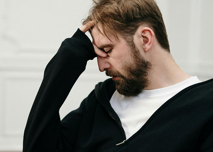 Bearded man in black jacket looking distressed, illustrating the impact of dark medical secrets on mental health.