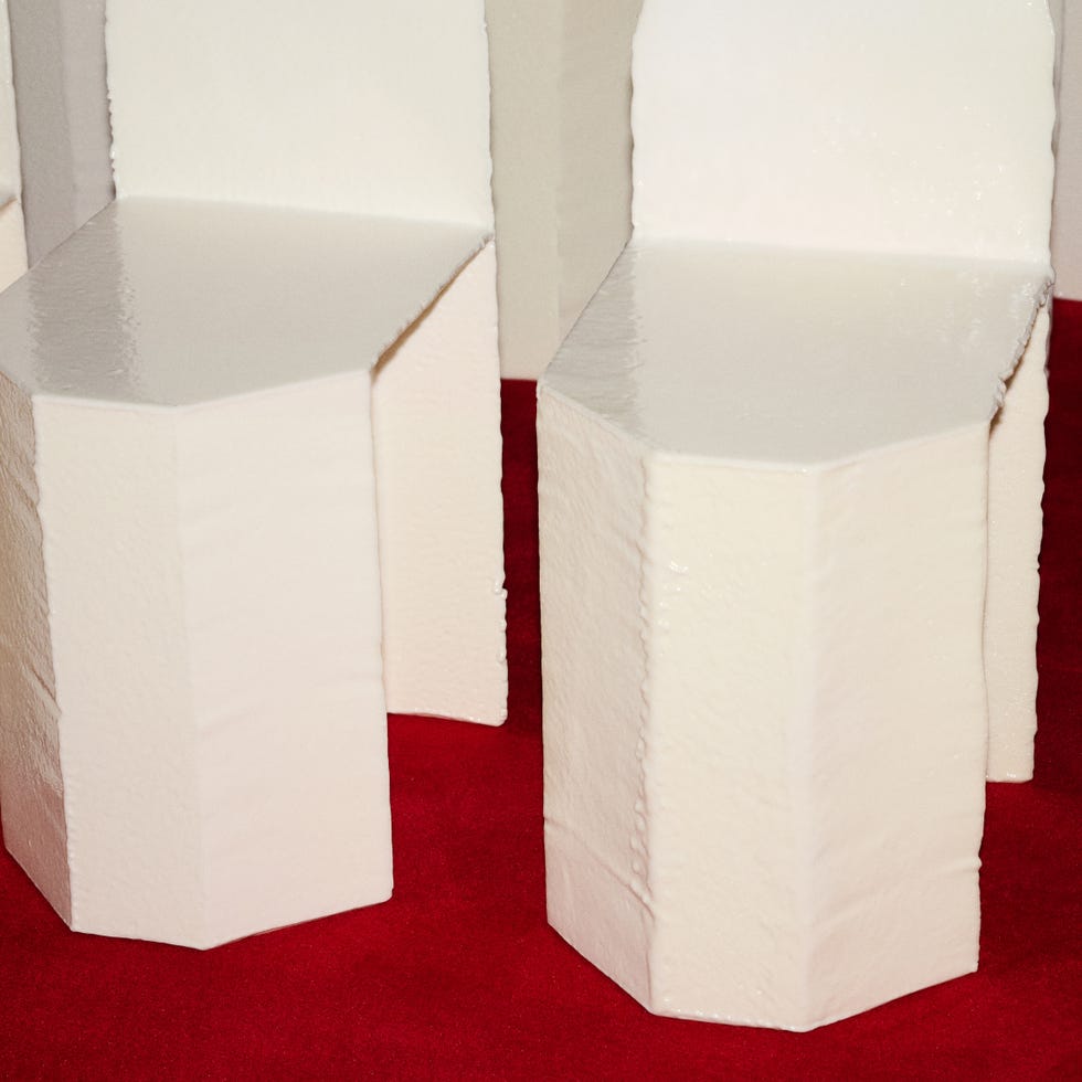 Geometric white stools on a red surface.