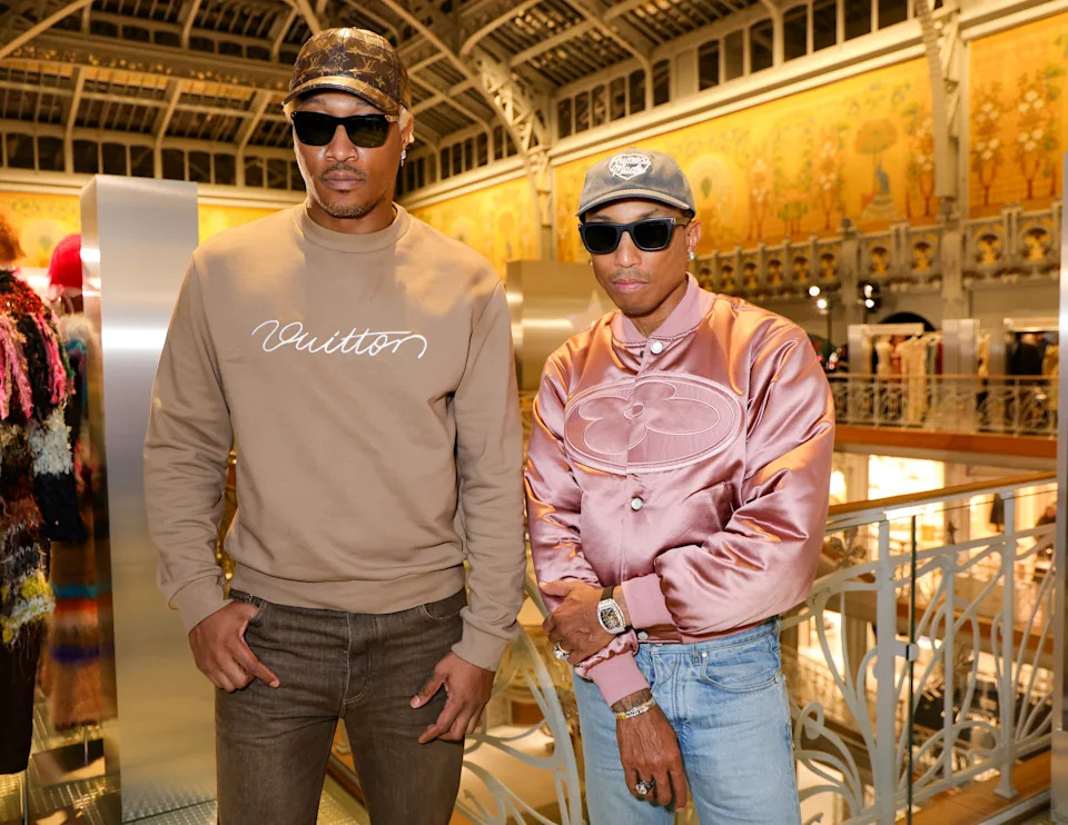 Two individuals wearing stylish sunglasses and casual clothing, standing inside a fashionable venue, likely a fashion event or store opening