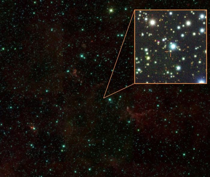 An image of a starry night sky, with blue glowing stars and red gas against a dark background. An orange boxout on the right shows a zoomed in area where the Gaia20ehk star system is.