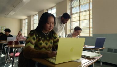 young woman seated at a classroom desk using a MacBook Neo