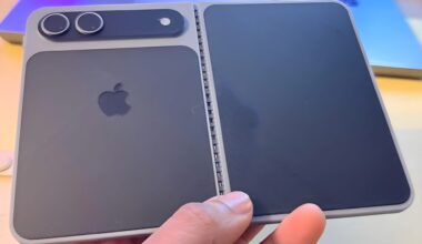 A person is holding a concept model of a foldable Apple device with a dual-camera setup and the Apple logo on the back.