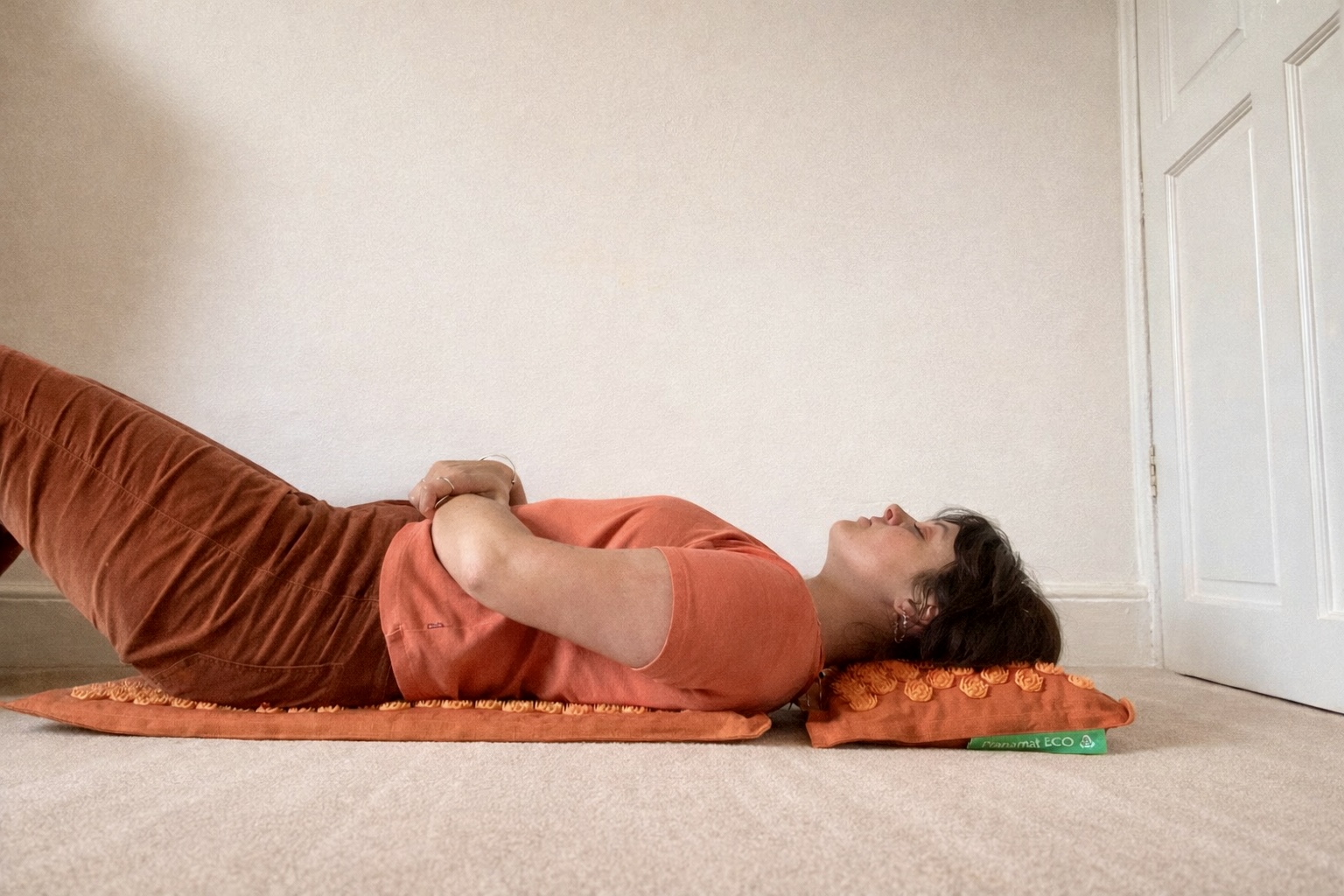 Lauren, a Tom's Guide writer, lying on her back on top of an orange Pranamat