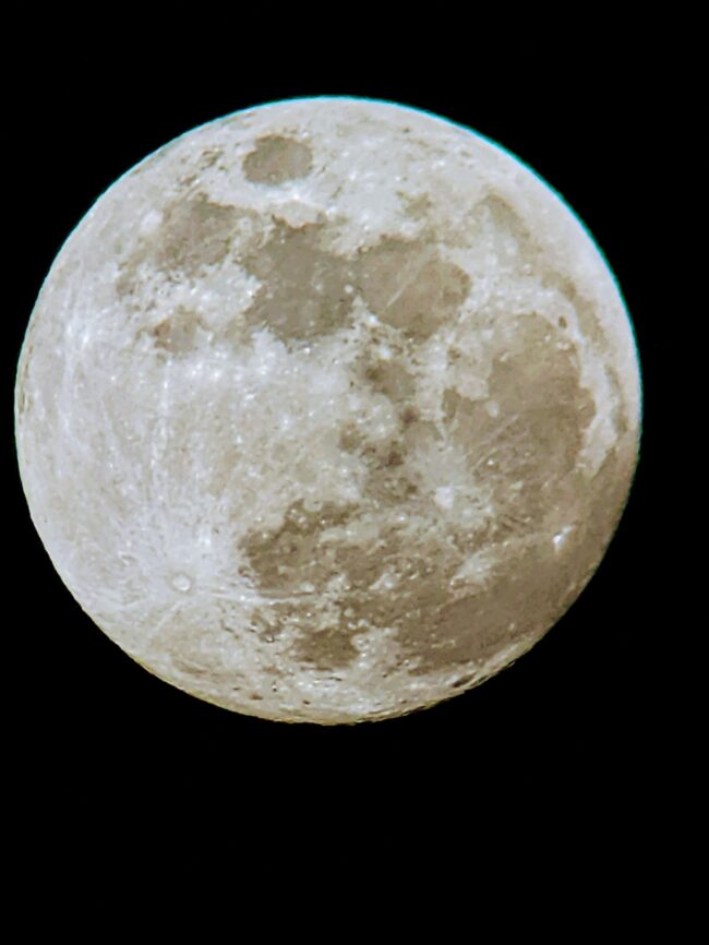 Bright moon with whitish and gray areas.