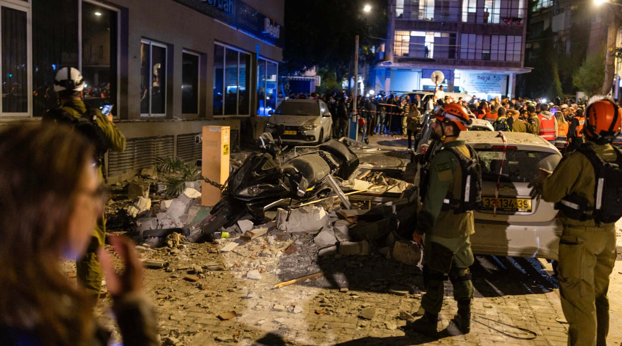 First responders work at the site of a building hit by an Iranian missile strike in Ramat Gan, on the outskirts of Tel Aviv, early on March 18, 2026.