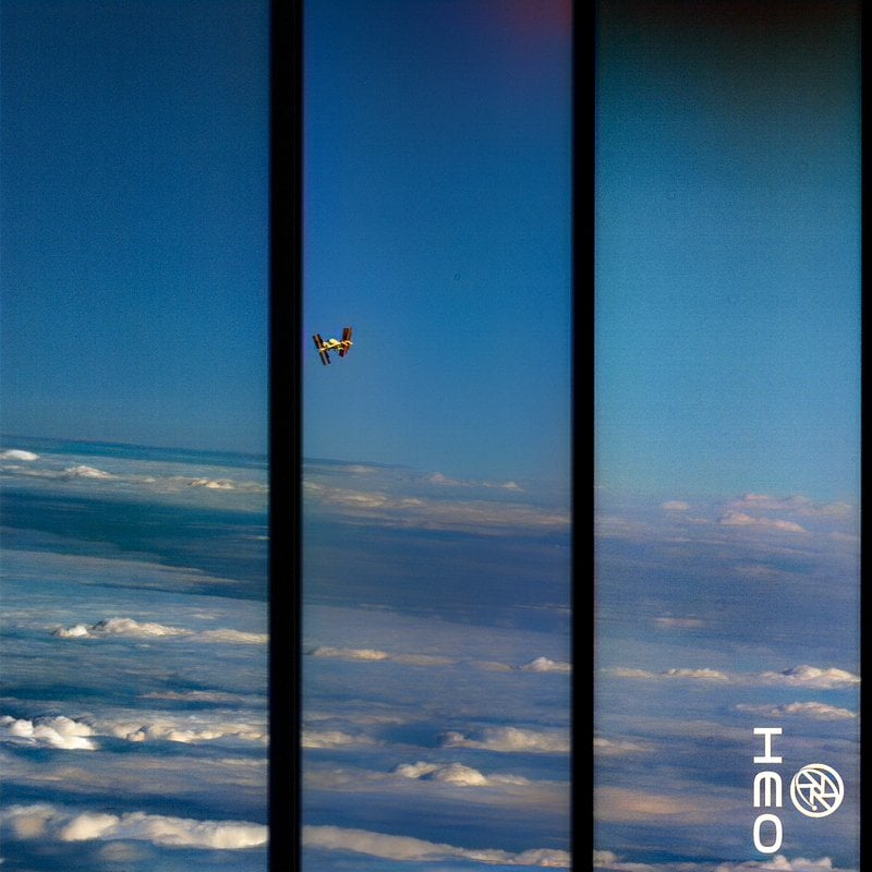 A small airplane flies above a blanket of clouds, framed by three vertical dark window bars. The sky is blue with scattered clouds below. A white logo with "ONE" and a globe is in the bottom right corner.