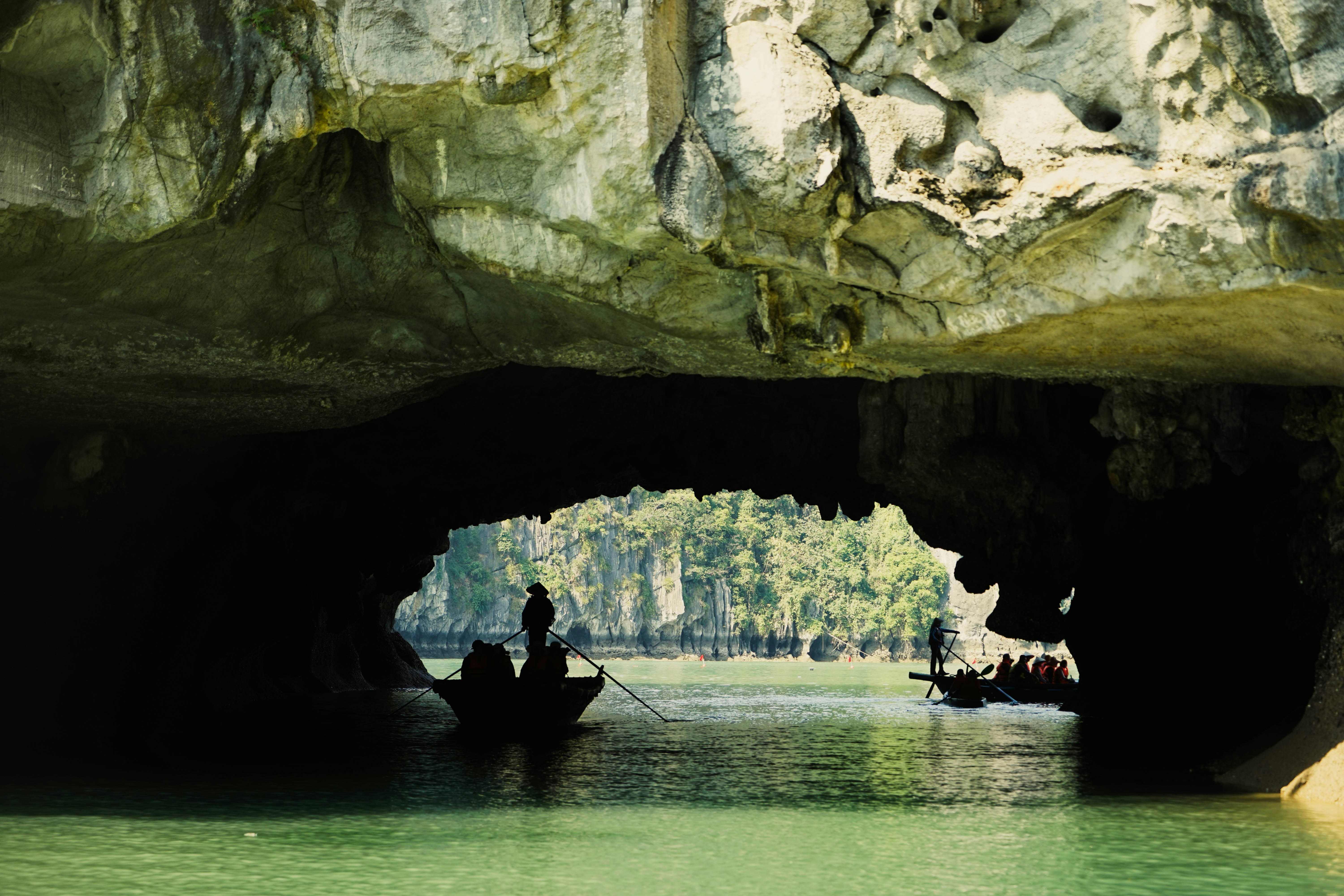 Rowing under a rocky arch beneath an island in Halong Bay on a day cruise.