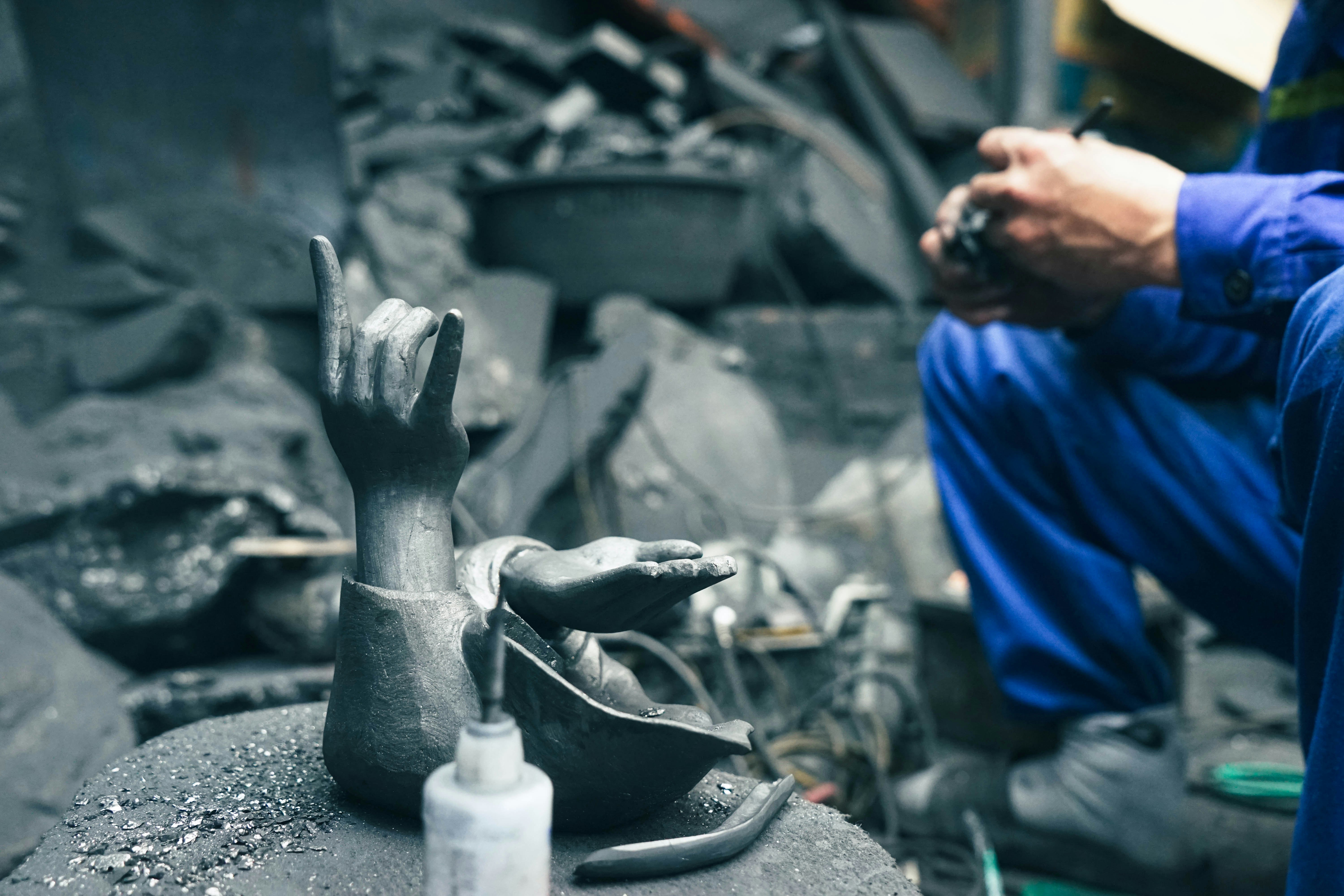 An artisan carving coal into the shape of human hands at a workshop in Halong City, Vietnam.