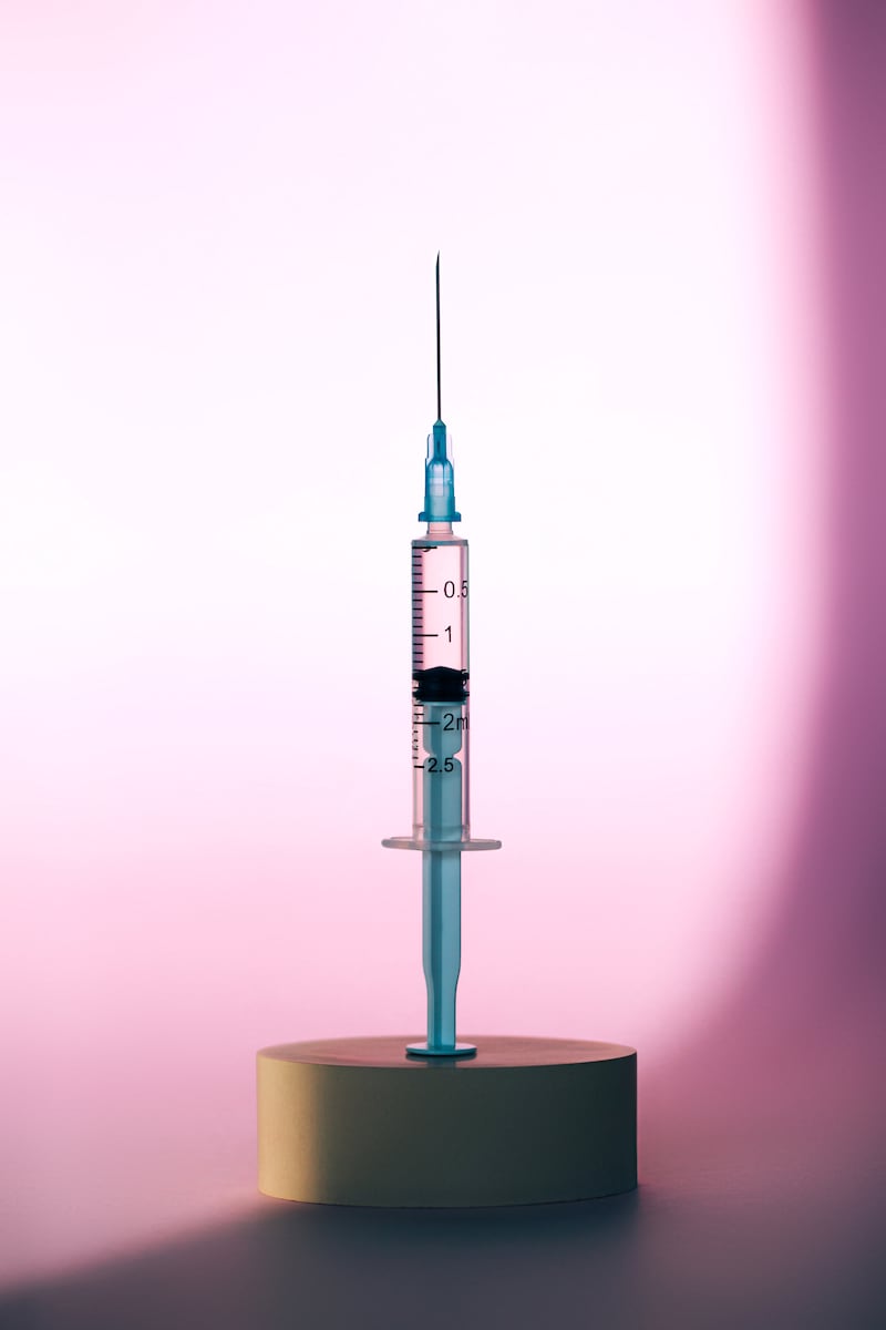 GLP-1 injection pen in front of a pink background