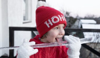 boy plays with a large icicle in winter, happily tasting it with his tongue hanging out.