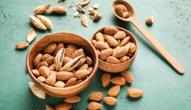 Bowls with tasty almonds on color background