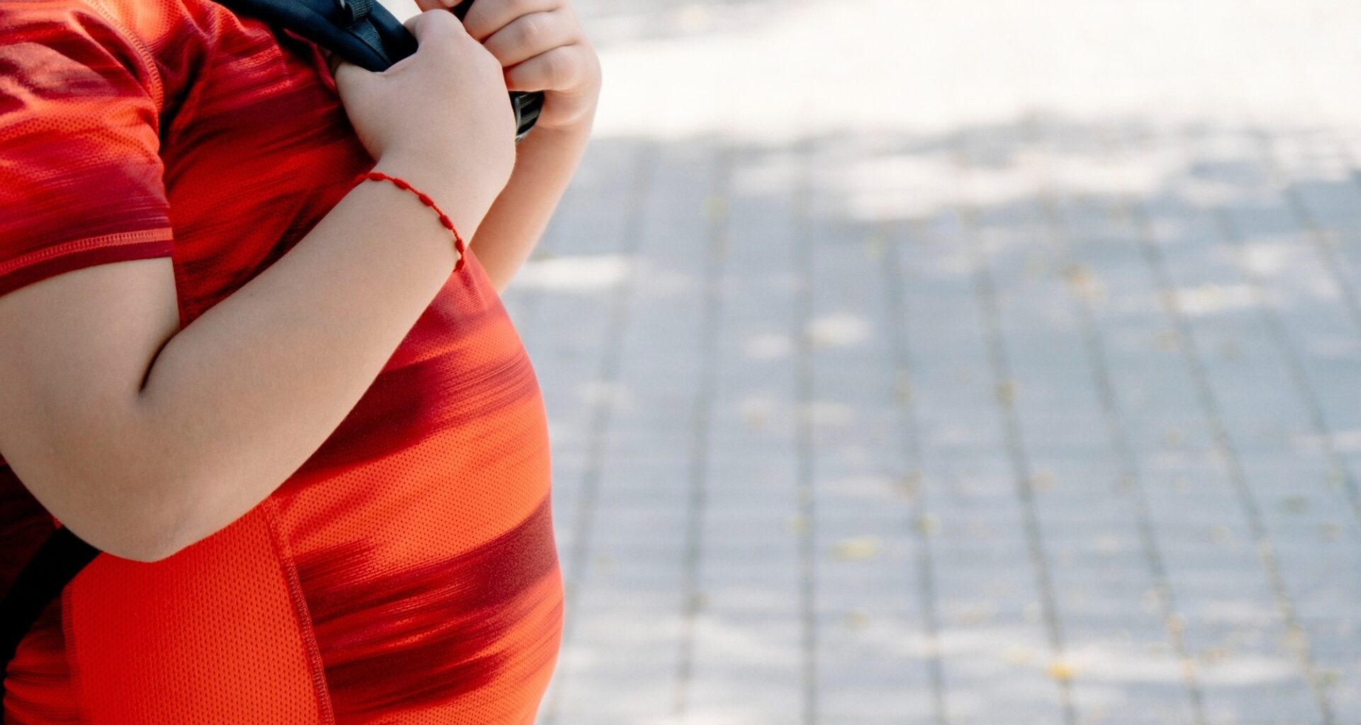 Childhood obesity concept. Boy with school bag with big belly.