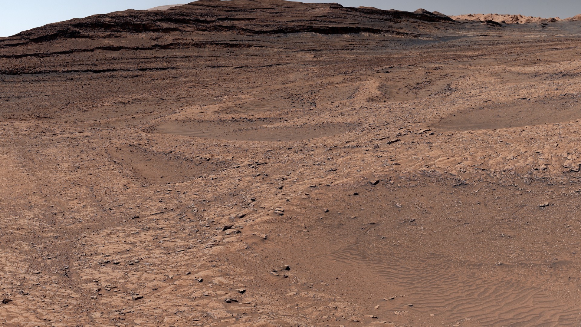 a red, dusty landscape with shallow ravines carved throughout it