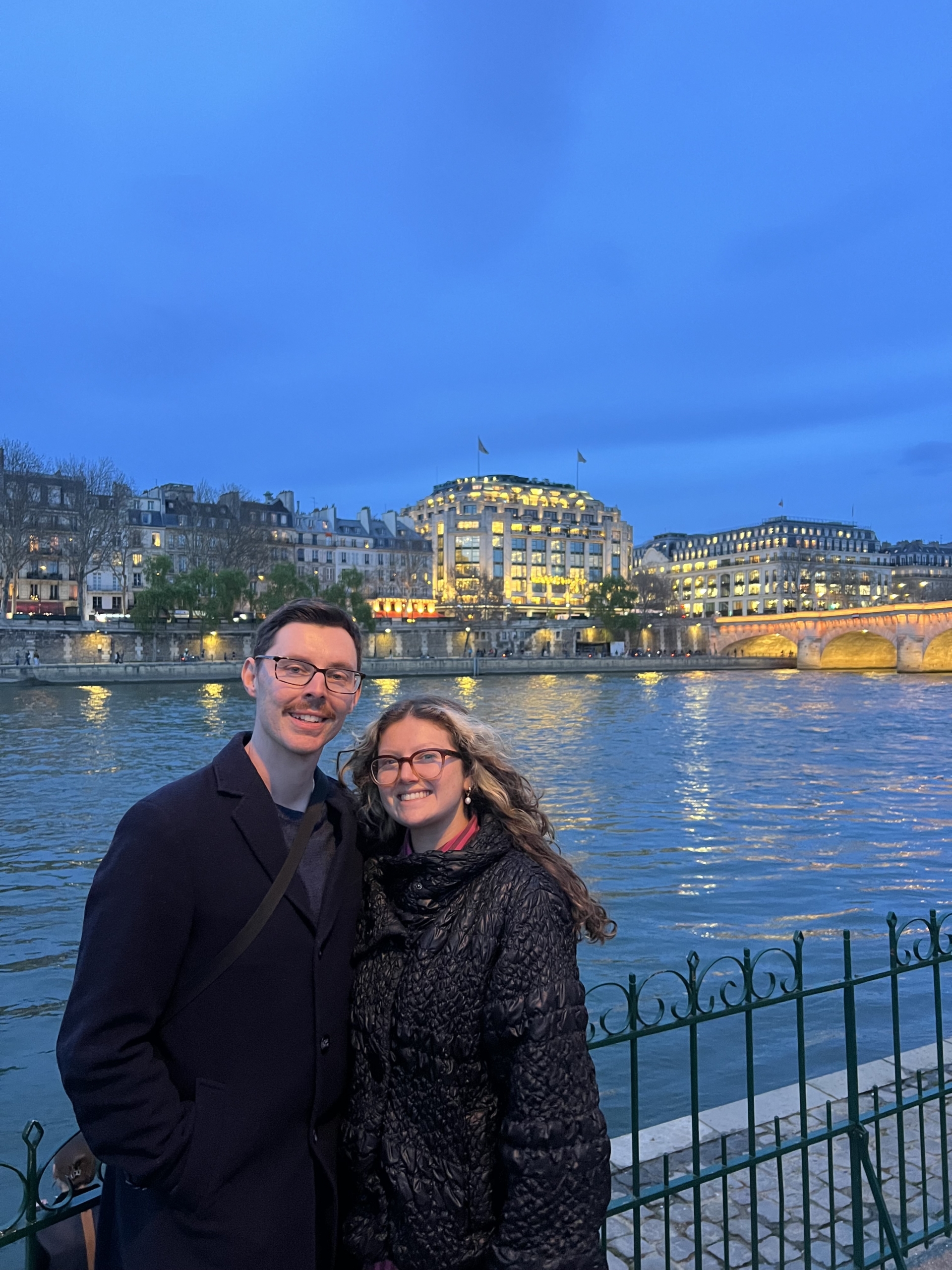 John Kerr and Peyton Johnson stand together in front of Seine River in Paris, France.