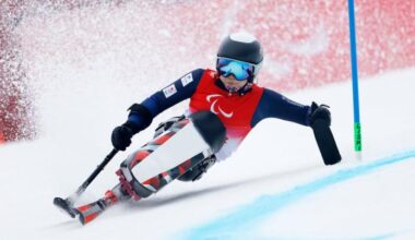 A female Para alpine skiing athlete is racing down the slope on a sit-ski