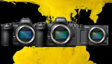 Three Nikon mirrorless cameras are lined up side by side, with their lens mounts exposed, against a background of vibrant yellow paint splashes on black.