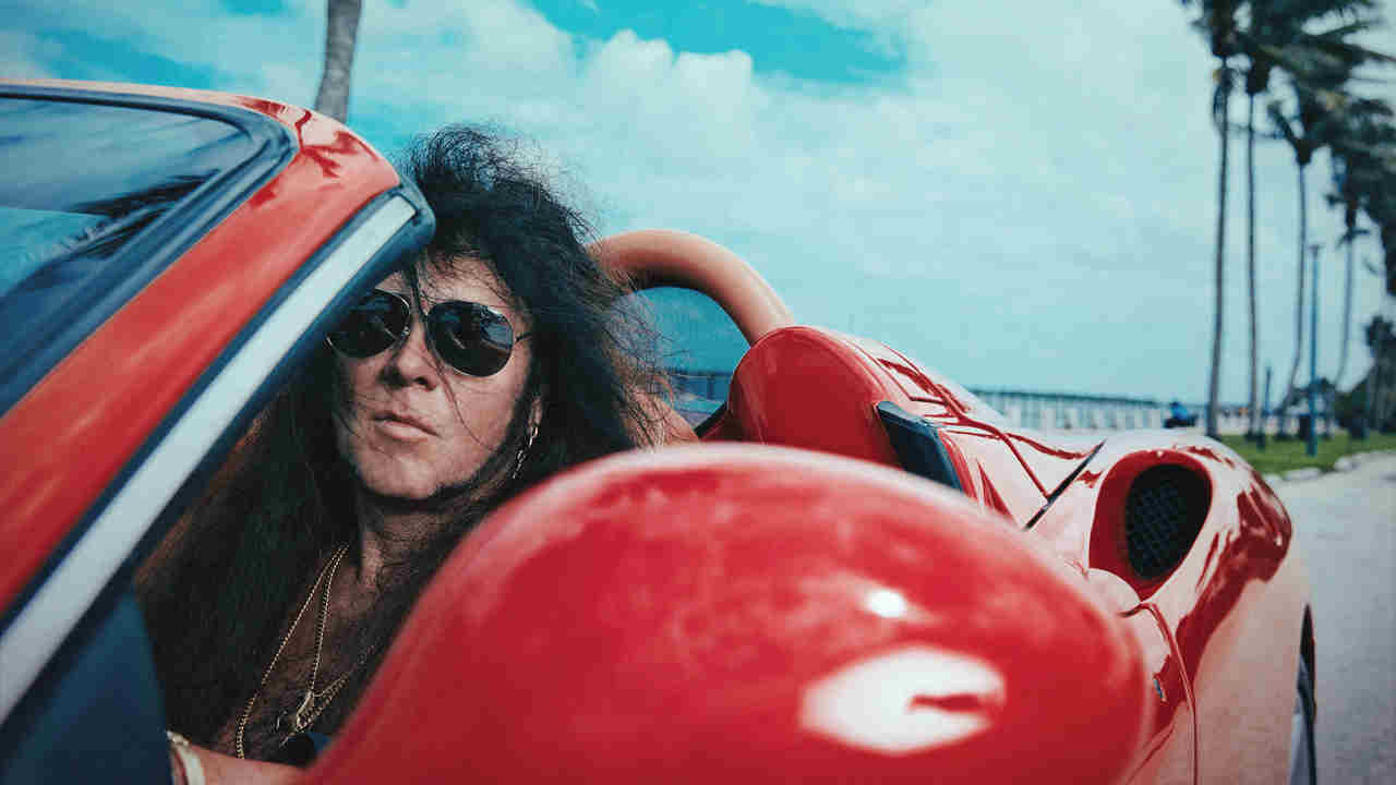Yngwie Malmsteen posing for a photograph in a sports car