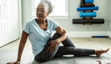 woman sitting on an exercise mat wearing leggings and tshirt in a seated twist facing the camera with her eyes closed.