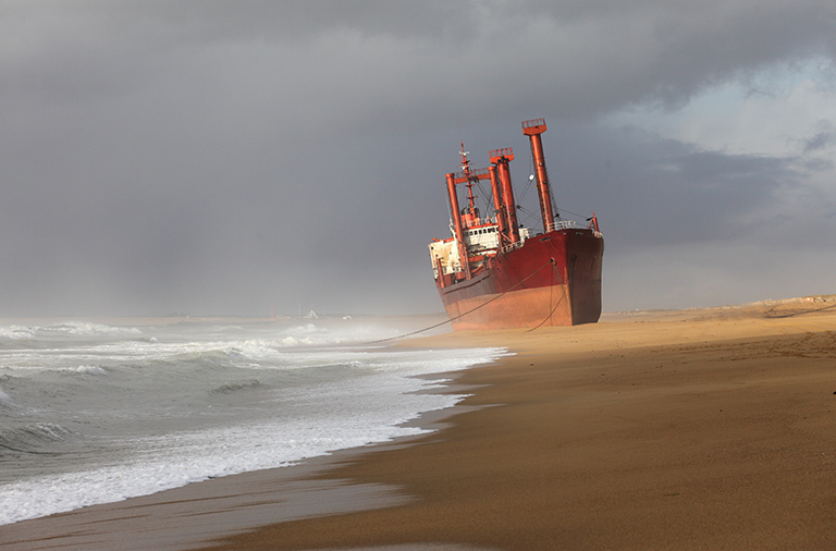 A large cargo ship stranded on a beach.