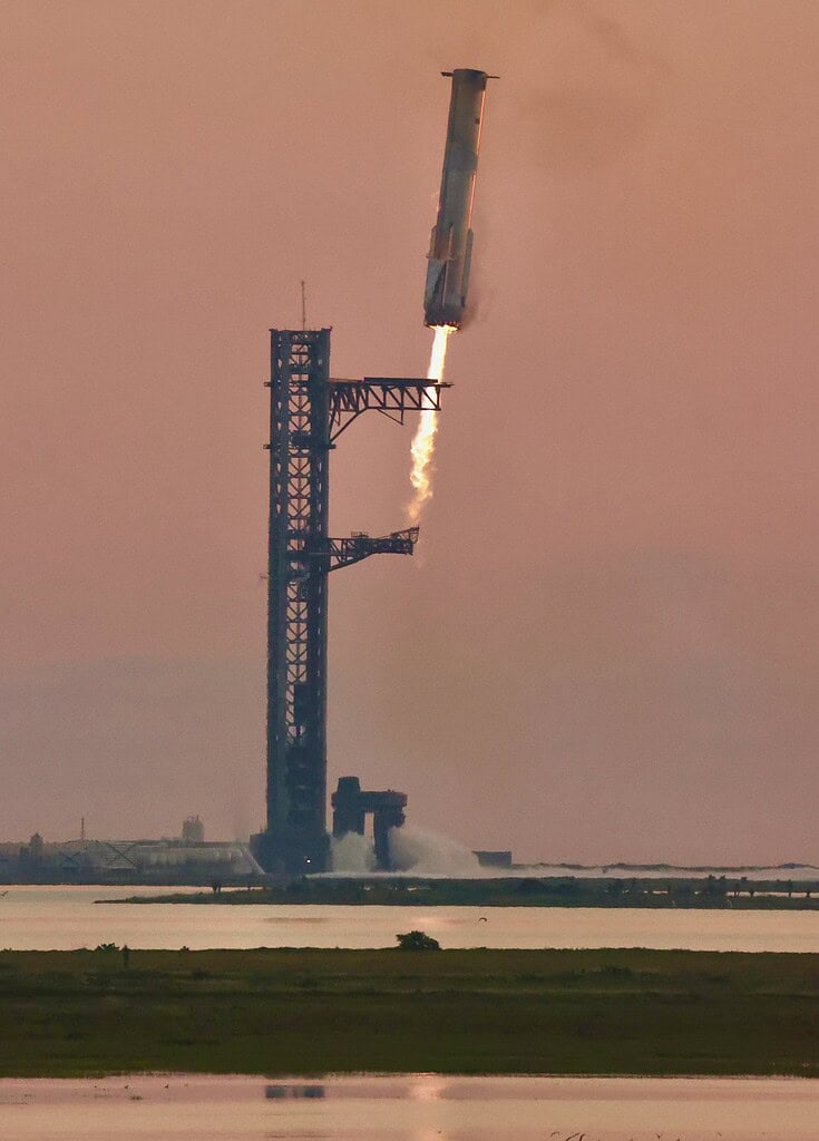 Rocket launch from spaceport with flame and smoke against pink sky.