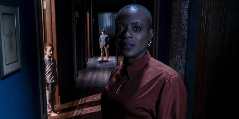 Hannah Grose stares down the halls of Bly Manor, with Miles and Flora behind her