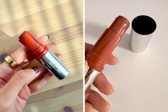 An individual holds a Haus Labs Color Fuse Glassy Blush Balm Stick with a silver base and a reddish-brown cap, in a side-by-side view.