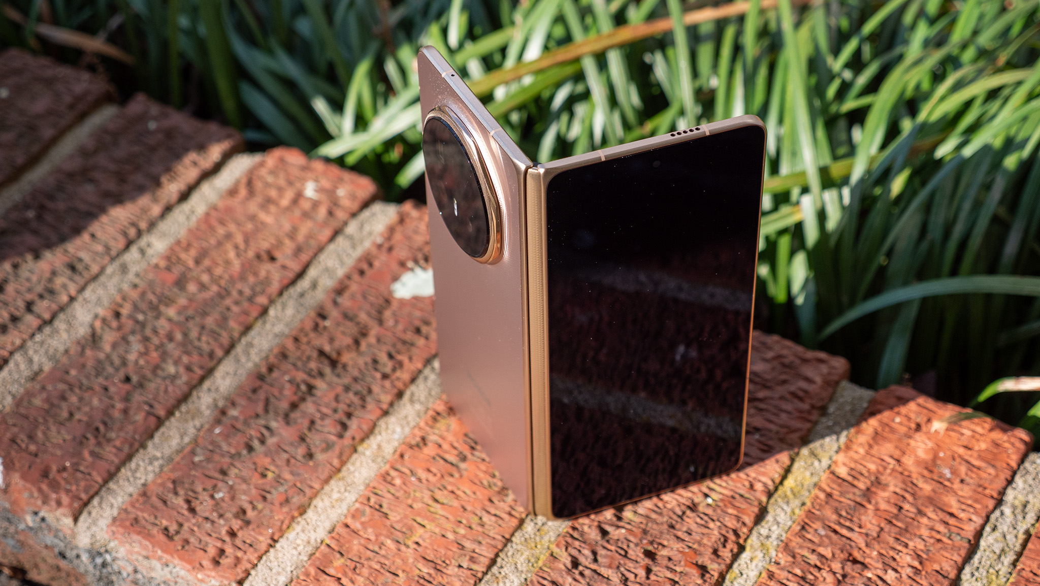 A gold Honor Magic V6 tented on a brick wall