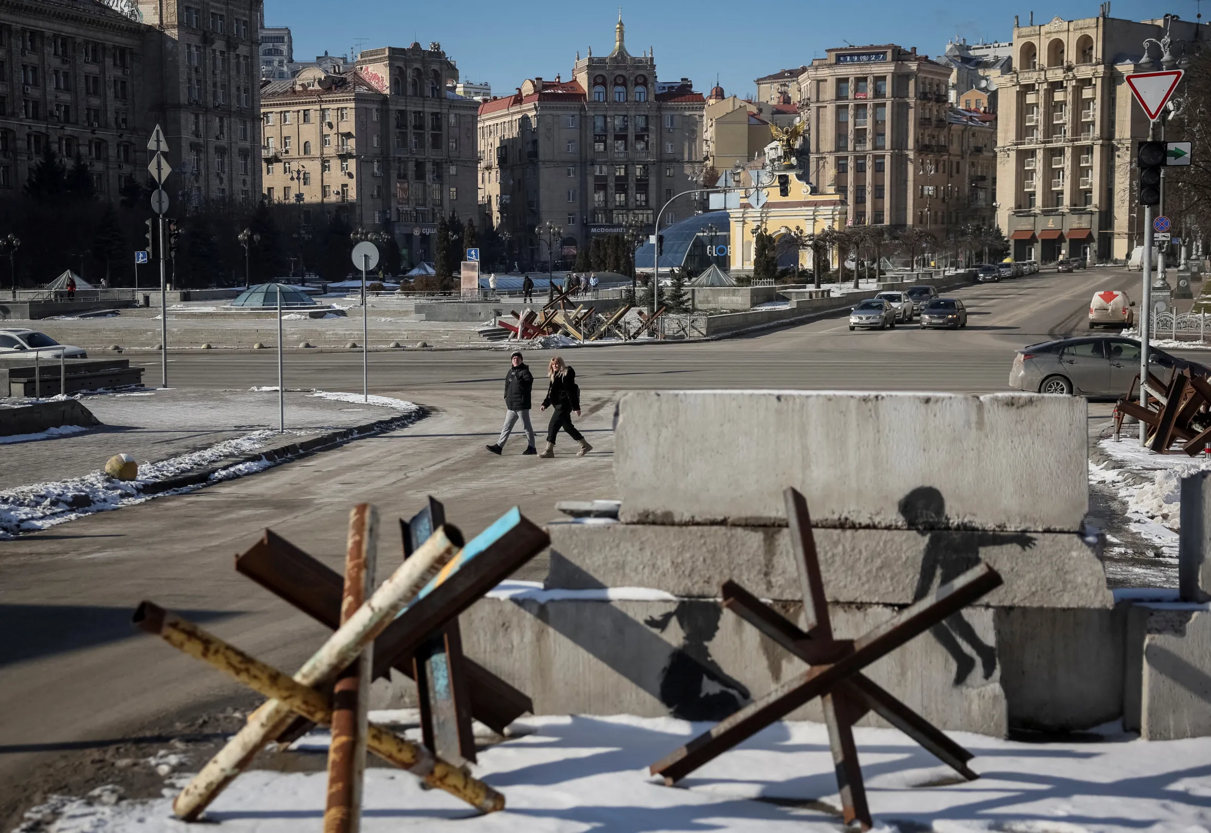 People walk past Banksy's anti-tank barrier graffiti in central Kyiv, Ukraine.