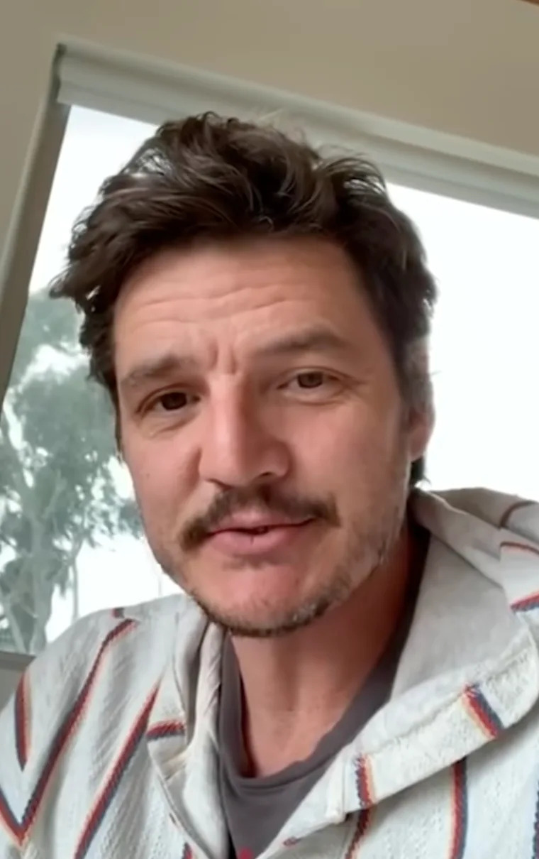 A person is looking at the camera, indoors. They are wearing a casual striped hoodie