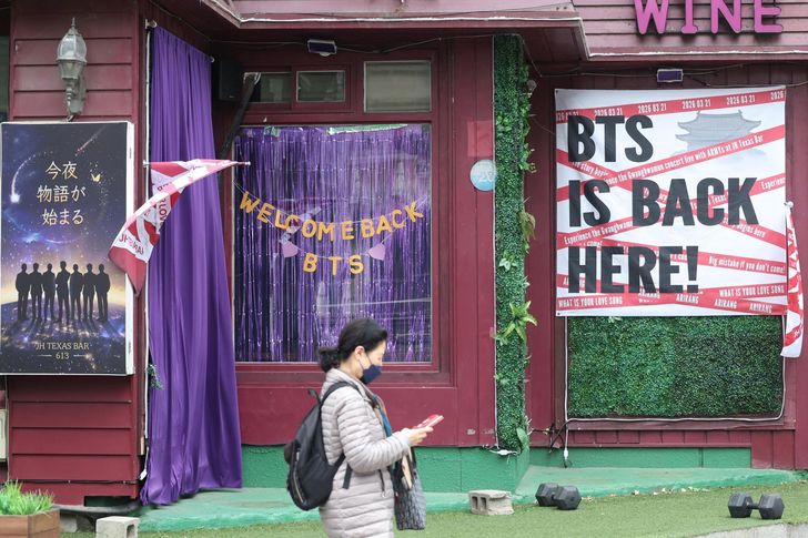 A pedestrian walks past JH Texas Bar displaying welcome messages for BTS in Jung District, central Seoul, Sunday, ahead of the boy band’s full-group comeback concert at Gwanghwamun Square this Saturday after three years and nine months. Yonhap 