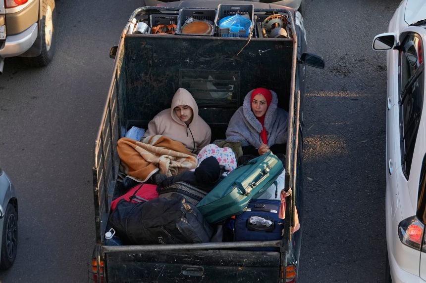 Displaced people fleeing Israeli strikes in southern Lebanon sit on a pickup at a highway that links to Beirut, in the southern port city of Sidon, on March 2, 2026.
