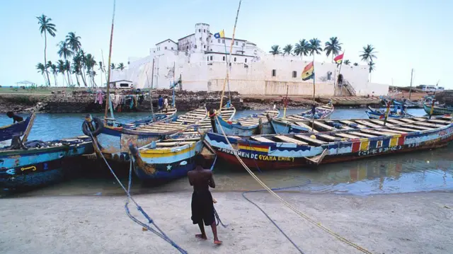 Colourful boats float in front of di Elmina slave fort