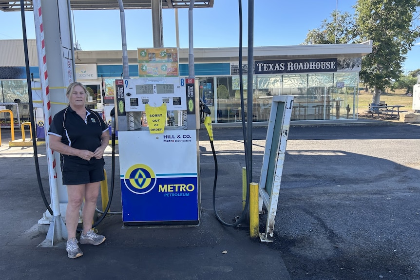 A woman standing by a fuel bowser which is out of service
