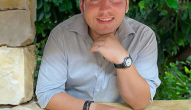 man leaning through an opening in a stone wall