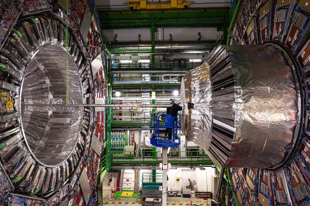 A person, center, right, is dwarfed by the size of the CMS experiment at the Large Hadron Collider, shown here in 2024. Credit: CMS/CERN