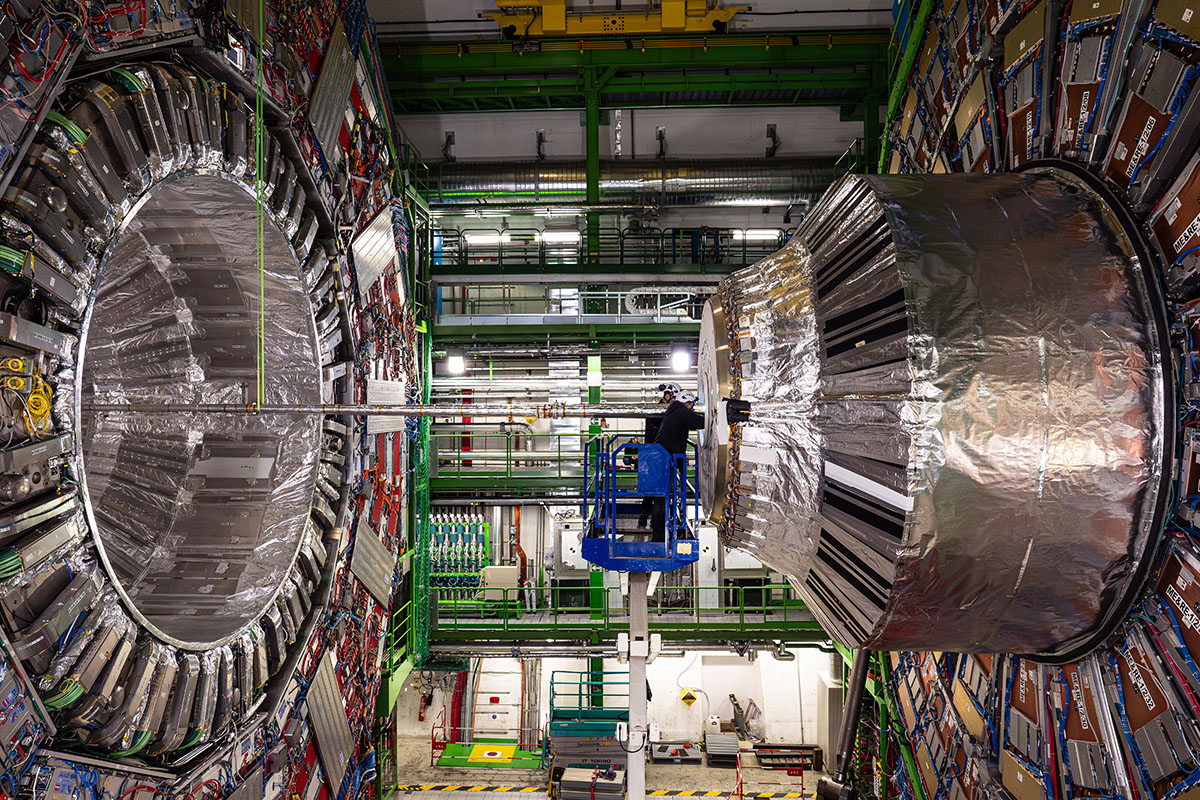 A person, center, right, is dwarfed by the size of the CMS experiment at the Large Hadron Collider, shown here in 2024. Credit: CMS/CERN