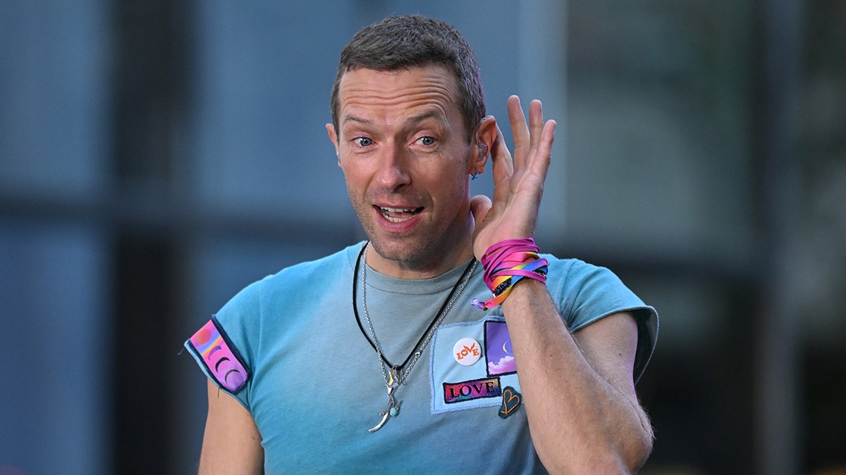 Chris Martin puts his hand to his ear