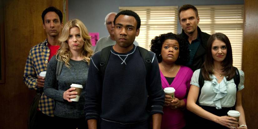 'Community' cast with coffee cups standing behind an angry Troy, all facing camera.