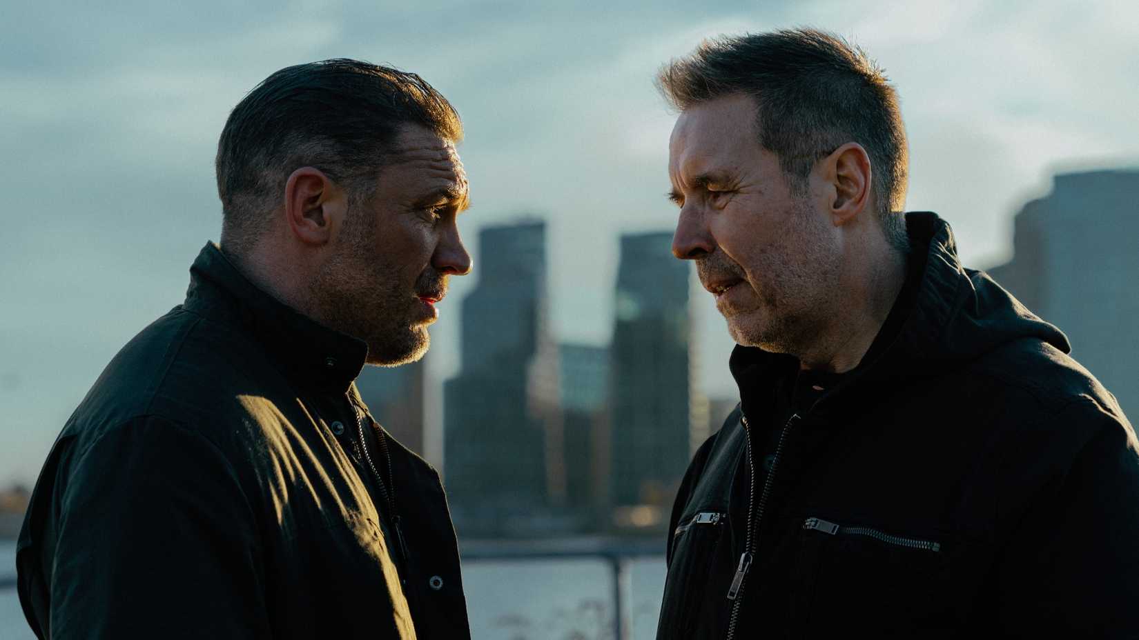 Two characters in profile in front of a cityscape in the crime drama MobLand.