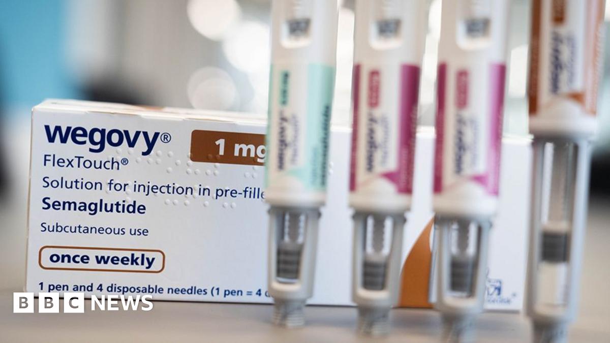 Close up of a counter top with a white box of Wegovy weight loss drug behind four out of focus pens used to inject the drug