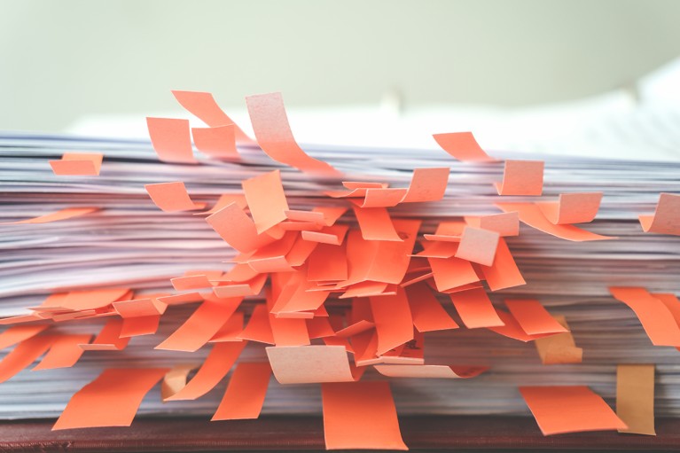 A large stacked paper document with multiple sticky note flags attached to various pages.