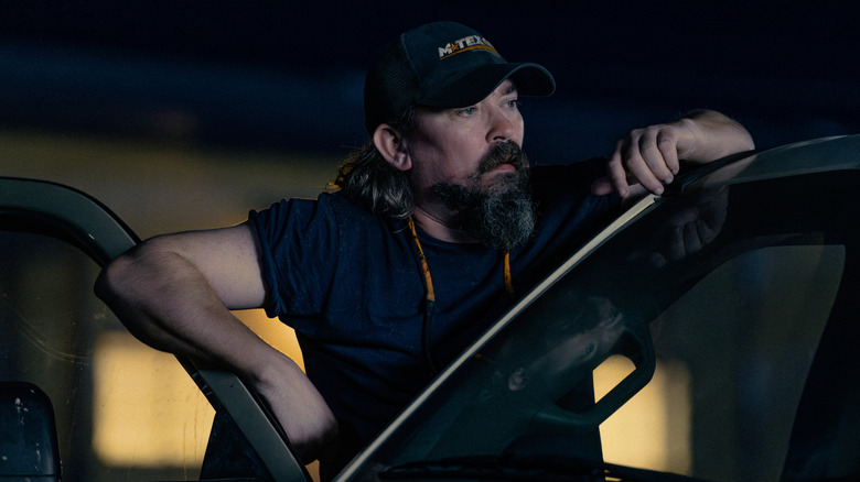 Dale leaning on the open door of a car in 