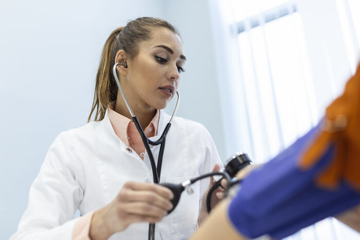 Female doctor using a stethoscope and blood pressure monitor, revealing behind-the-scenes feelings and opinions of doctors.