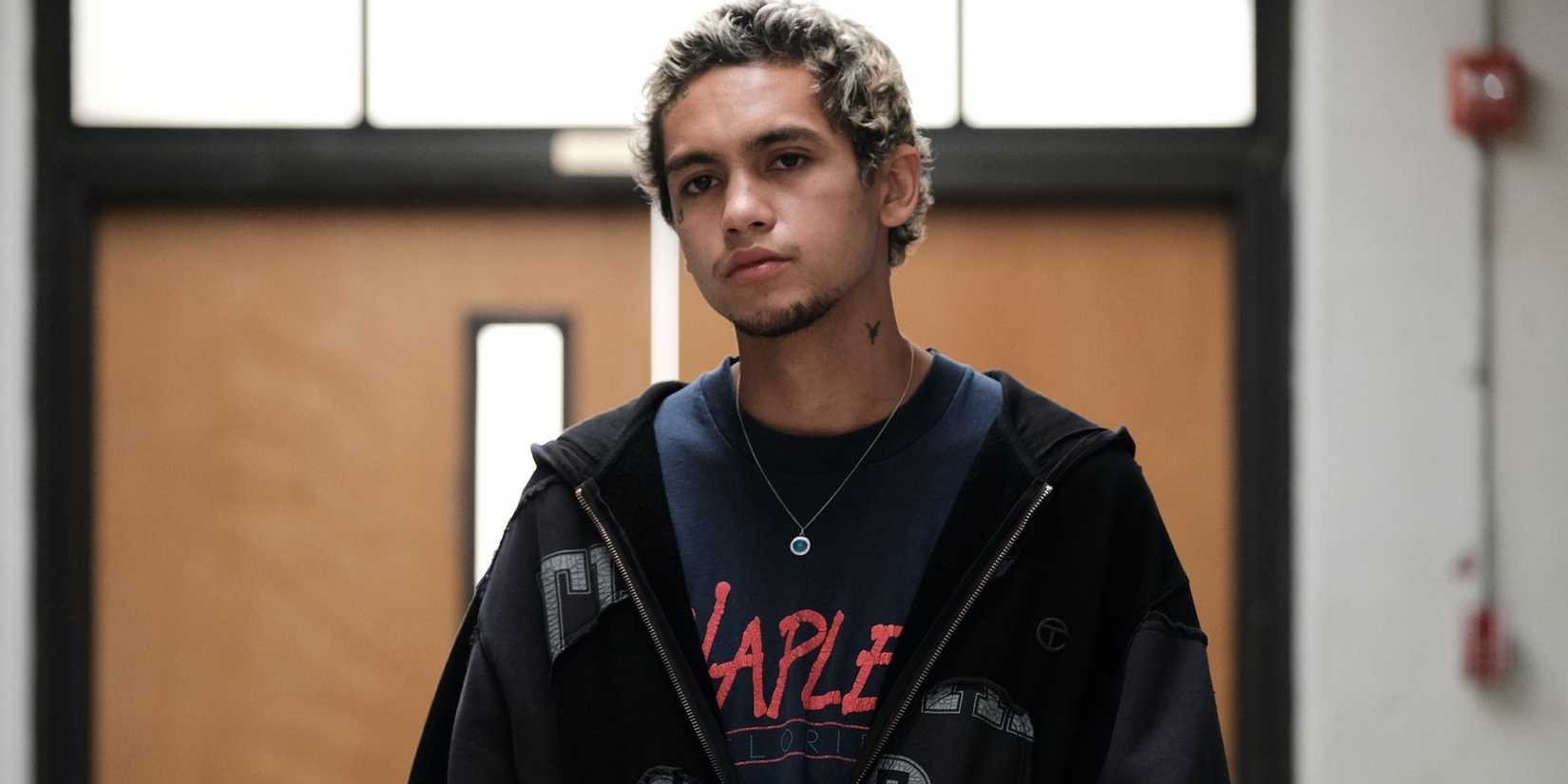 Dominic Fike as Elliot walking down a hallway in a school building in Euphoria